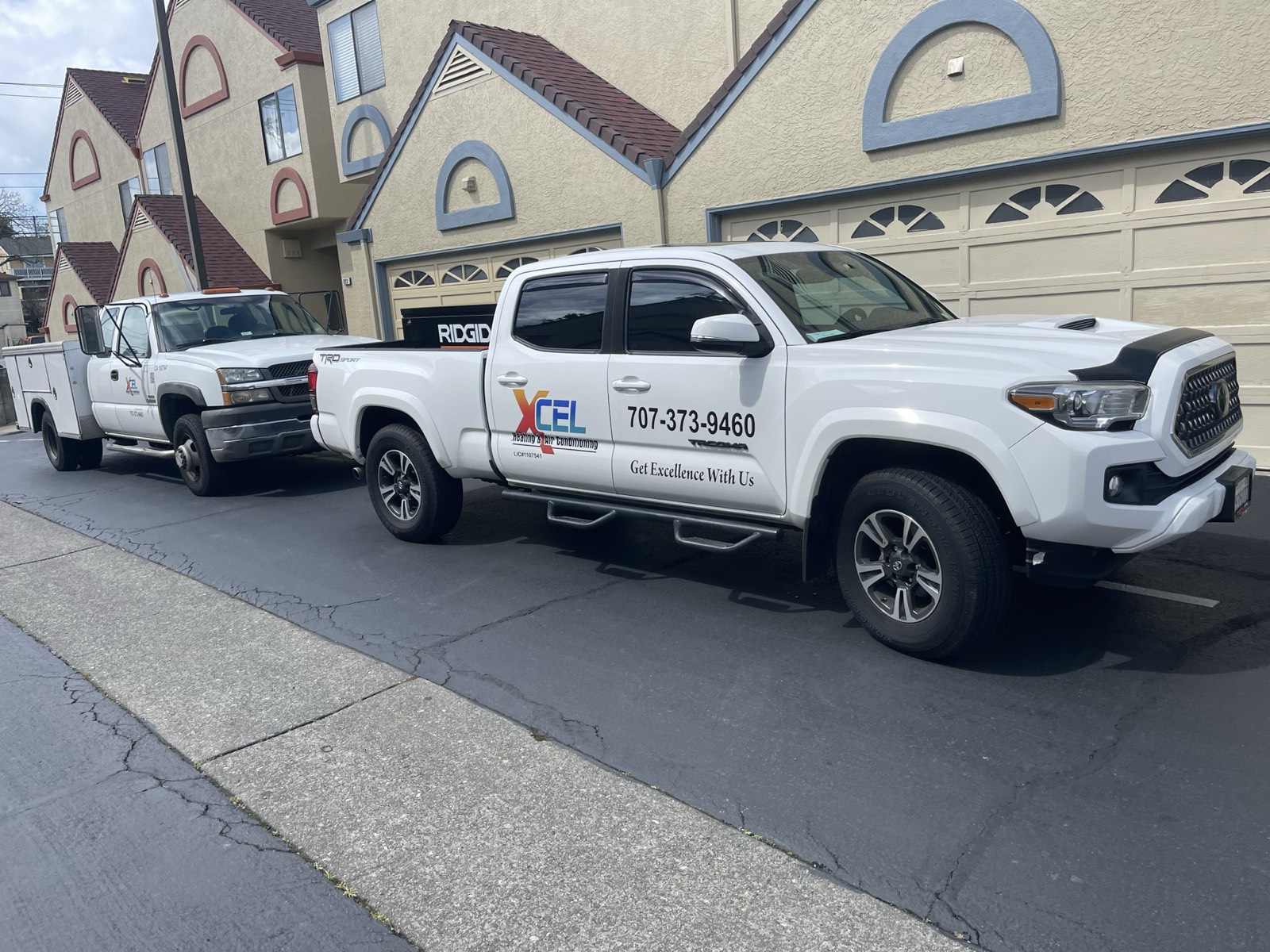 XCEL Heating and Air Conditioning service trucks parked at a residential job site